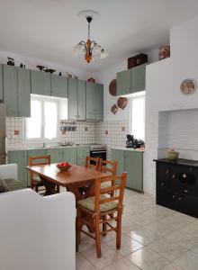 阿波罗尼亚Casa Centrale的厨房配有绿色橱柜和木桌及椅子