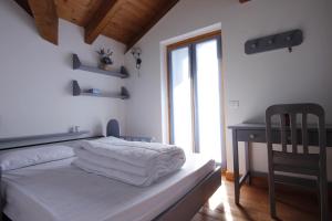 帕索罗莱LA PULCE INNEVATA - Dolomiti Affitti的一间卧室配有一张带白色床单的床和一张书桌。