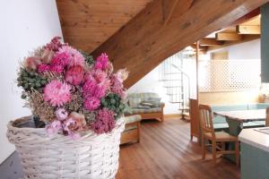 帕索罗莱LA PULCE INNEVATA - Dolomiti Affitti的客厅里装满粉红色花的篮子