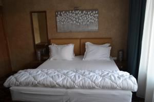 贝尔格莱德Garni Hotel Chicha - Winery ŠKRBIĆ的卧室内的一张带白色床单和枕头的床