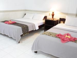勒吉安芒加巴厘岛酒店的两张位于酒店客房的床,上面有红色的鲜花