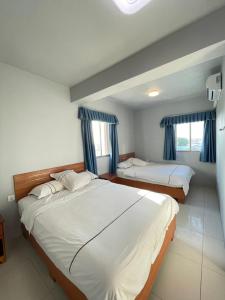 库尔克岛卡尔克岛海滩酒店的卧室内的两张床,配有蓝色窗帘