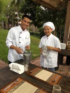 琅勃拉邦On The Mekong Resort的桌上准备食物的男人和女人