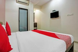 孟买Hotel Amfahh - Andheri West Railway Station的一间卧室配有一张带红色枕头的白色床和电视。