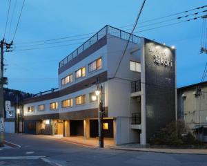 郡山Tabist Onsen Petit Hotel Yukori Bandai Atami的一座高大的建筑,旁边有一个标志