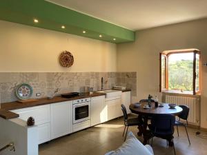 Gagliano CastelferratoLa Casa Delle Olive的厨房配有白色橱柜和桌椅