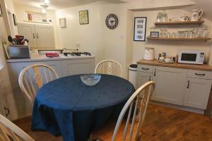 贝克韦尔Anne Cottage, Bakewell, in the Peak District的厨房配有一张桌子,上面有蓝色的桌布