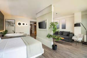 Néon RýsionHeaven Hotel Thessaloniki Airport的一间卧室配有一张床、一台电视和一张沙发