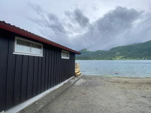 TresfjordFagervik Camping的靠近一大片水体的黑色建筑