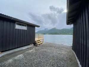 TresfjordFagervik Camping的水体旁边的黑色建筑