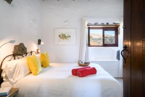 马赫La Casa del Medianero的一间卧室配有白色的床和黄色及红色枕头