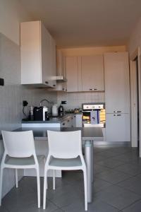 佩罗Rho Fiera Milano - Popy House的厨房配有白色橱柜和白色椅子