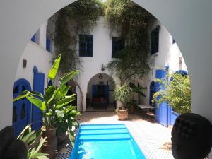马拉喀什里亚德查梅陇摩洛哥传统庭院住宅旅馆的一座拥有蓝色和白色墙壁的建筑前的游泳池