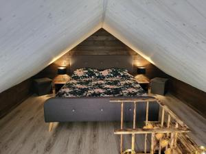 维尔扬迪Tiny house near Viljandi lake的阁楼中央的一张床位,配有两张桌子