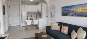 德尔锡伦西奥海岸Precioso apartamento con piscina junto al mar的一间带蓝色沙发的客厅和一间厨房