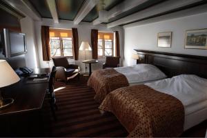 AnsHotel Kongensbro Kro的酒店客房带两张床、一张桌子和椅子。
