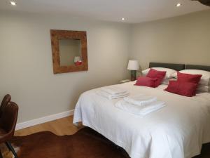 泰特伯里Trouble House的一间卧室配有一张白色的床、红色枕头和镜子