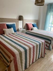 维戈Samil primera línea de playa的一间卧室配有两张带彩色毯子和枕头的床。