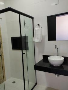 瓦尔任博尼塔Canastra Flat Hospedagem的一间带水槽和玻璃淋浴的浴室