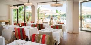 察夫塔特Hotel Supetar的一间设有白色桌椅和窗户的用餐室