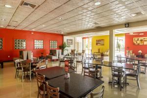 麦卡伦Clarion Inn near McAllen Airport的一间带桌椅和红色墙壁的餐厅