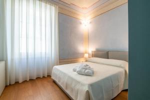 比萨La Suite del Borghetto的一间卧室设有两张带白色床单的床和窗户。