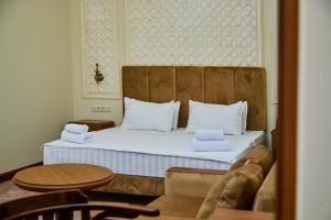 撒马尔罕Sangzor Boutique Hotel的卧室配有带白色枕头和桌子的床