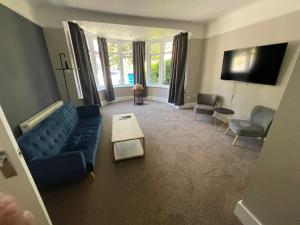 伯恩茅斯Bayside GuestHouse的客厅配有蓝色的沙发和桌子