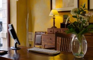 波凯兰特L'安国拉酒店的一张桌子,上面有电脑显示器和花瓶