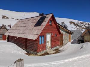 福伊尼察Koliba Nazif Softić的雪上带太阳能屋顶的红色小屋