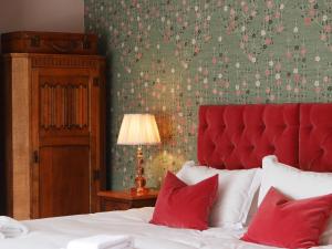 吉尔福德德拉蒙德奥尔伯里宾馆的一间卧室配有一张带红色床头板和红色枕头的床