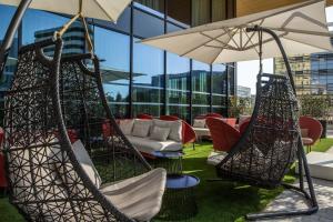 尼斯Crowne Plaza - Nice - Grand Arenas, an IHG Hotel的天井配有秋千椅和遮阳伞。
