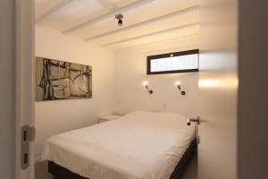 迪斯胡克霍夫克安兹度假屋的卧室配有白色床,墙上挂着灯