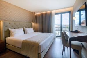 波尔图Oca Oriental Porto Hotel的配有一张床、一张书桌和一扇窗户的酒店客房