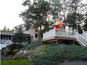 乔治湖Pinebrook - Three Bedroom House的甲板上戴着五颜六色的伞的人