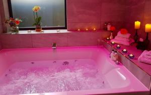 格兰奇奥沃桑茨格兰奇精品酒店 的浴室内粉红色的浴缸及粉红色的照明
