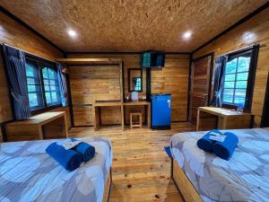 Tha KradanPhu Naphat Resort的小屋内带两张床和一张书桌的房间
