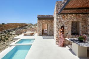 皮尔戈斯Santorini Sky, The Retreat的站在带游泳池的房子边的女人