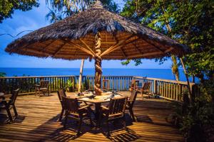 阿洛陶Tawali Leisure & Dive Resort的甲板上配有桌椅和大遮阳伞