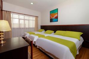 昆卡利迪策之家旅馆的一间卧室配有两张床、一张桌子和一盏灯。