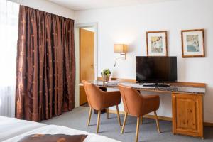 阿罗萨Cristallo Arosa Hotel的酒店客房配有带电视和椅子的书桌