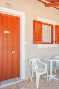扎金索斯镇Petros Giatras - Rooms的红色的门,位于带桌椅的房间