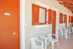 扎金索斯镇Petros Giatras - Rooms的一间设有橙色门、白色椅子和桌子的房间