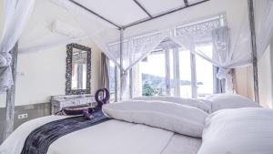艾湄湾Waenis Sunset View Hotel and Restaurant, Amed, Bali的一间卧室配有一张天蓬床和窗户