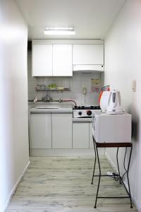 西归浦市西归浦梦幻森林度假屋酒店的厨房配有白色橱柜和带烤面包机的桌子。