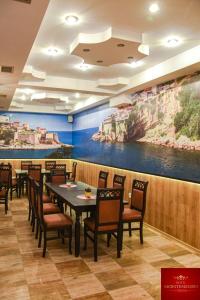 斯特鲁加Hotel Montenegro的一间带桌椅的用餐室和一幅画