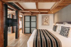 蒂涅Les Suites – Maison Bouvier的一间卧室设有一张大床和木制天花板。