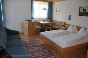 Sankt Lorenzen im LesachtalPension Oberhof的一间卧室配有一张床、一张沙发和一张桌子
