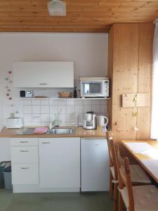 KuchelmißApartment Kletterrose am Krakower See的厨房配有白色橱柜、微波炉和桌子
