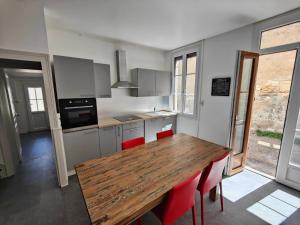 谢尔河畔努瓦耶Maison Val de Cher的厨房配有木桌和红色椅子